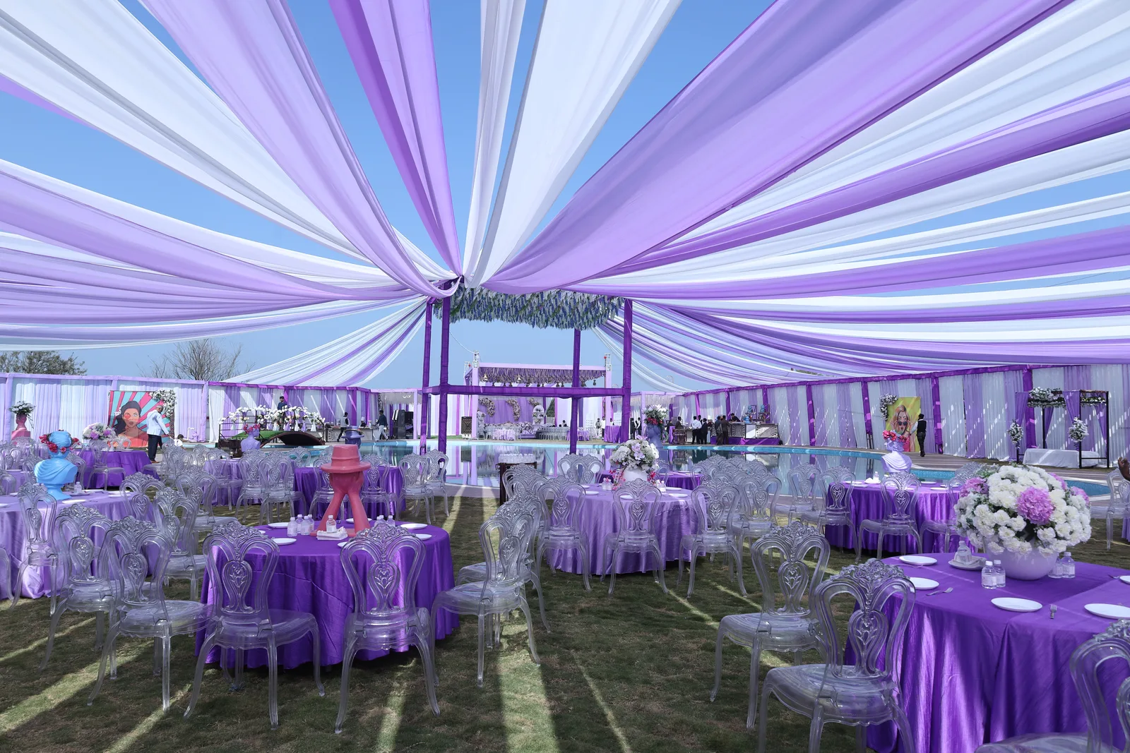 Evening corporate reception laid out beside the pool at Vetiver Grand, Jabalpur: draped canopies over round tables, dressed for a private party.