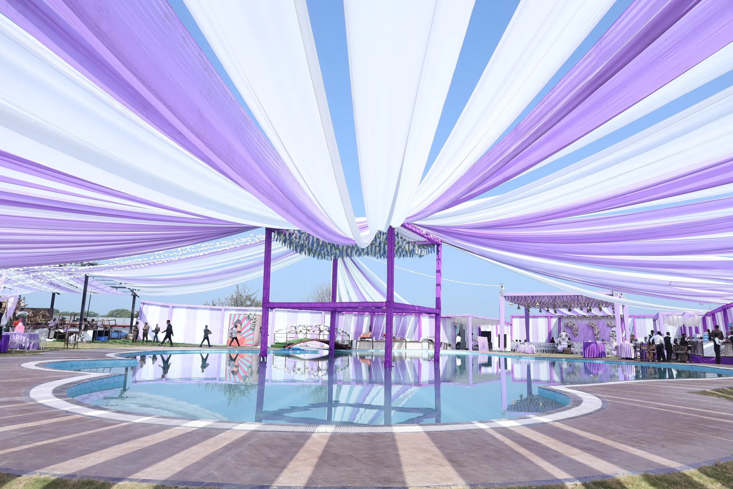 Poolside wedding reception at Vetiver Grand: canopies draped over the lawn pool, tables set at the water's edge.