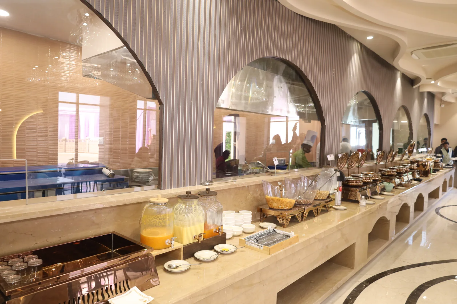 Marble buffet counters beneath a run of arched mirrors at Kasturi, the ground-floor pure vegetarian restaurant at Vetiver Grand.
