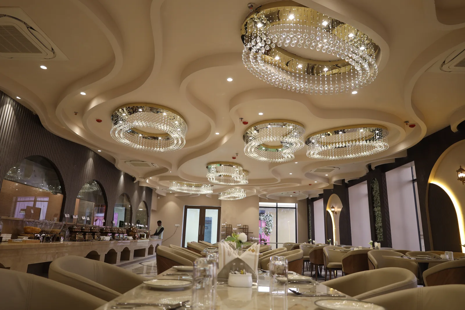 Kasturi's sculpted ceiling: rings of crystal-and-gold chandeliers set into cloud-form coves above the dining room.